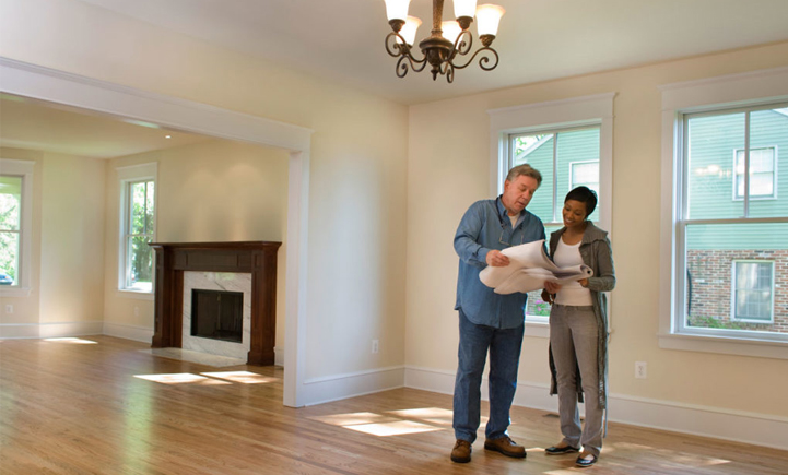 A Woman Talking With A Man Holding Blueprints